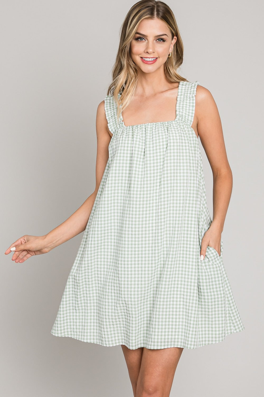Woman wearing a green checkered dress against a gray background