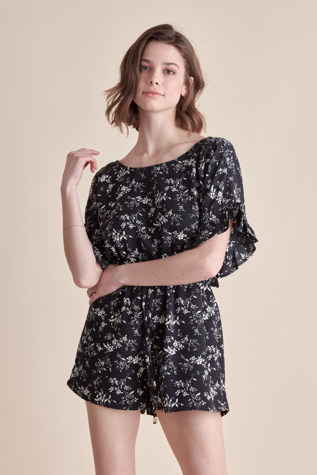 Woman wearing a black floral dress with puff sleeves on a beige background