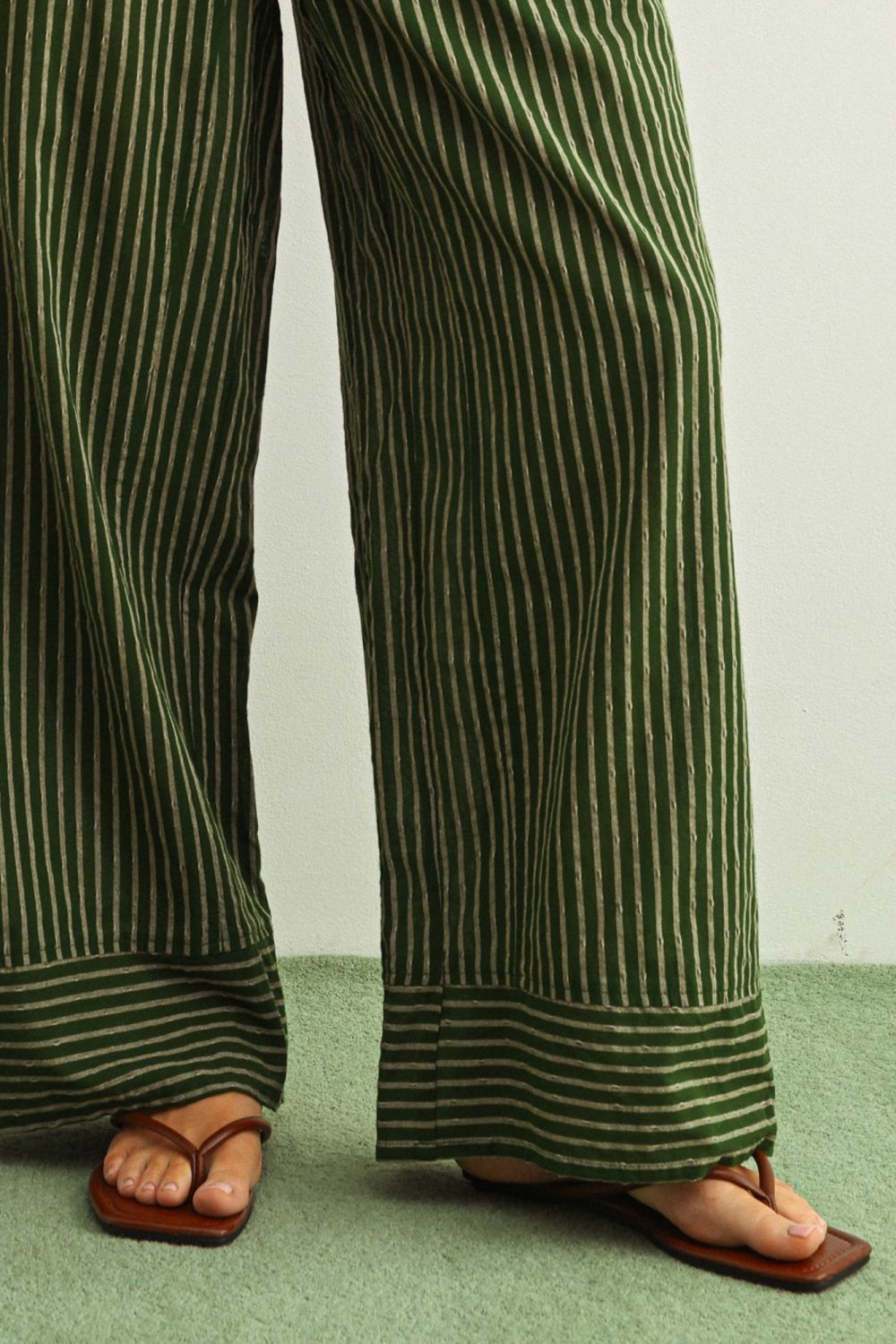 Green striped pants worn by a person on a light green floor.