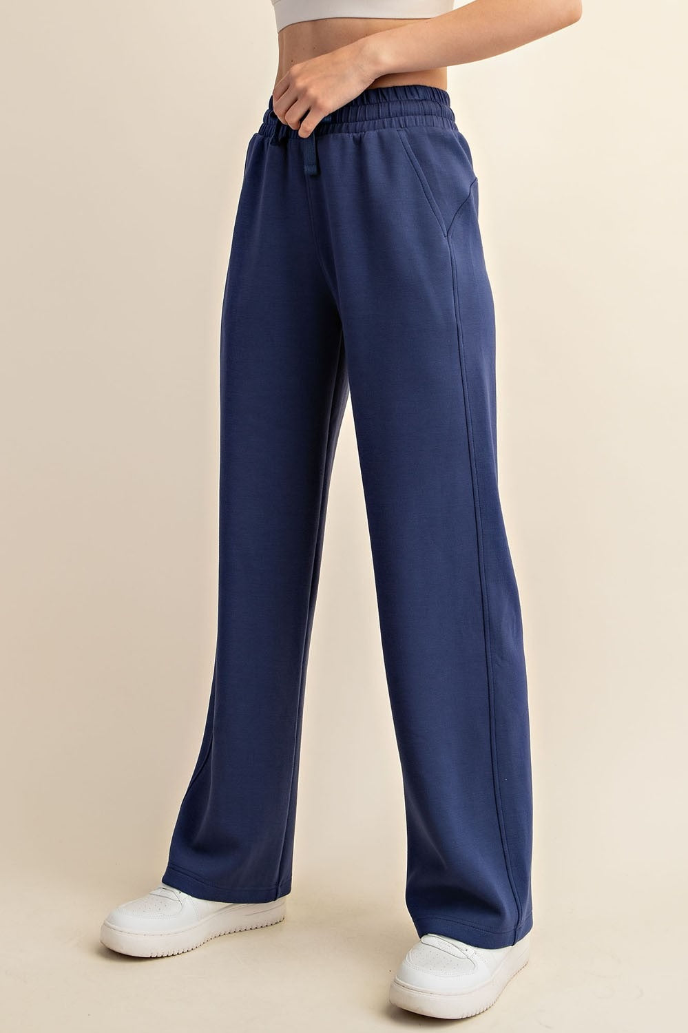 Navy blue wide-leg pants worn by a person on a beige background