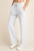White lounge pants worn by a person on a beige background