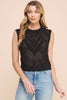 Woman wearing a black sleeveless knitted top with a beige background