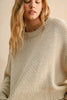 Woman wearing a beige sweater against a neutral background