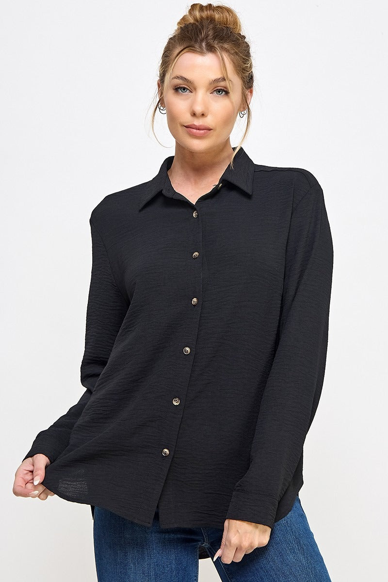 Woman wearing a black button-up shirt and blue jeans on a white background