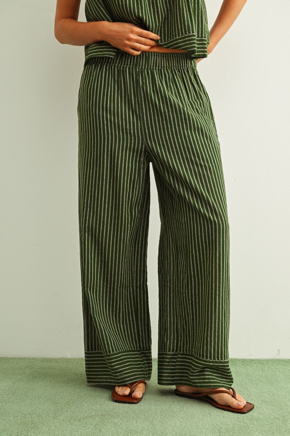 Green striped outfit worn by a person on a light green background