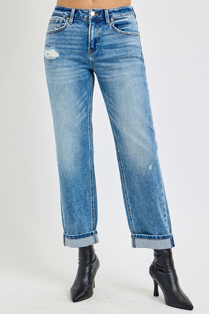 Blue jeans with a distressed look worn by a person on a light gray background