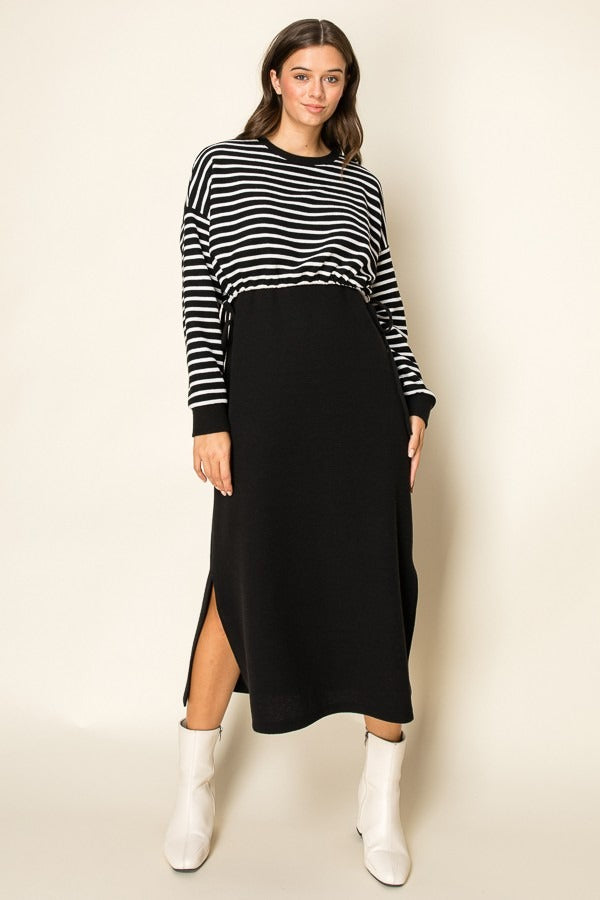Woman wearing a black and white striped sweater with a black skirt on a beige background