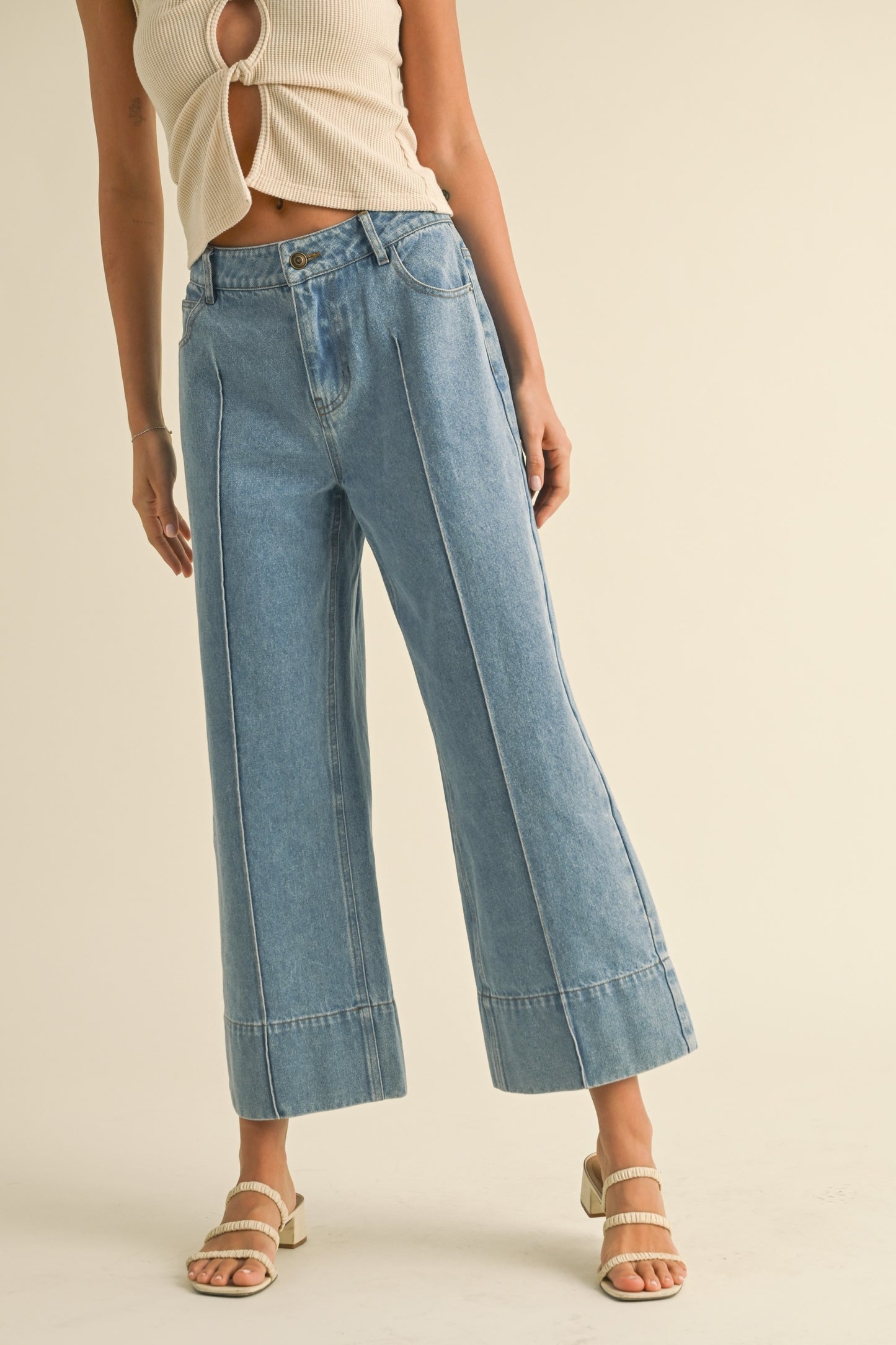 Person wearing light blue jeans on a beige background