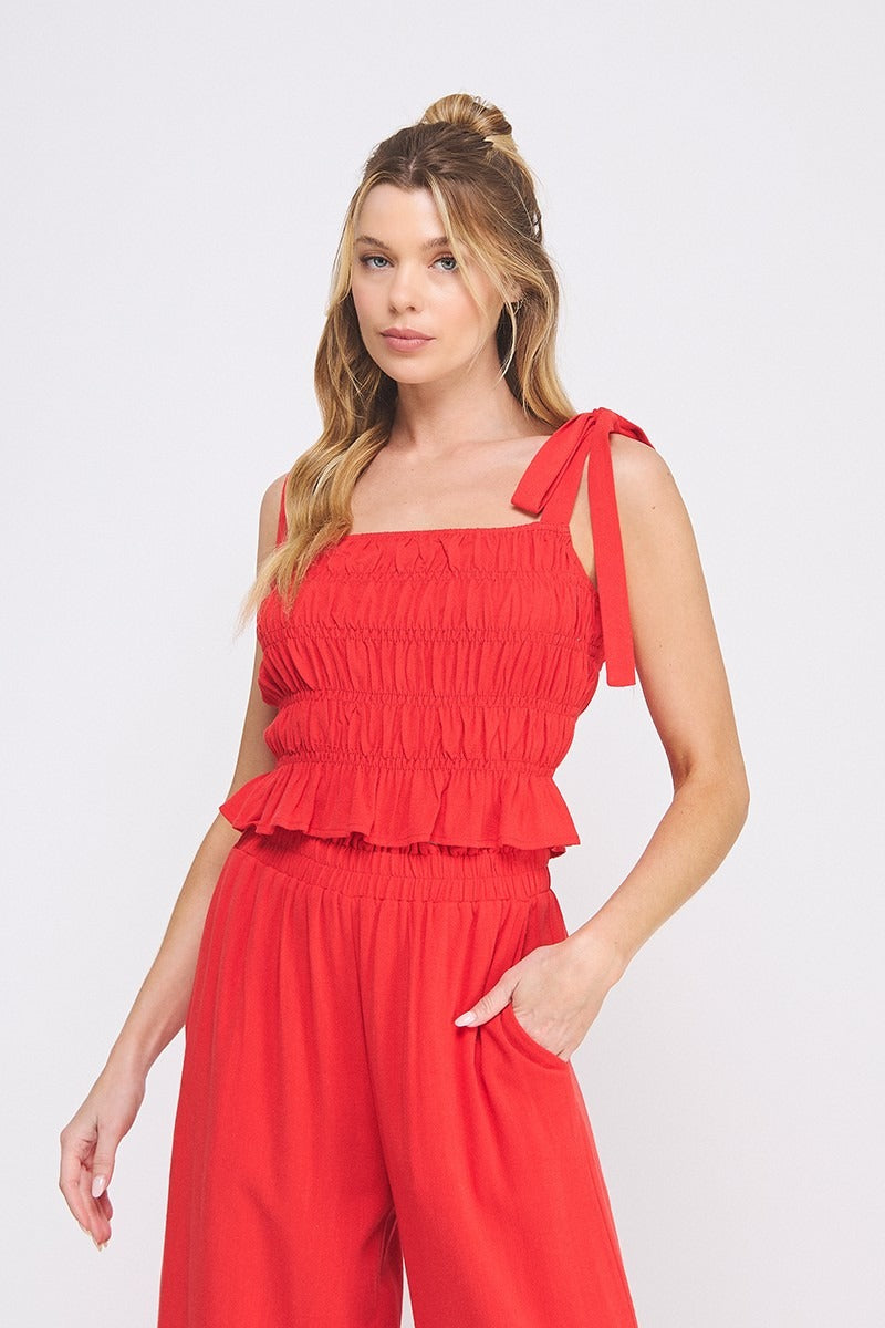 Woman wearing a red jumpsuit with ruffled top on a white background