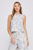 Woman wearing a sleeveless floral top and pants on a plain background