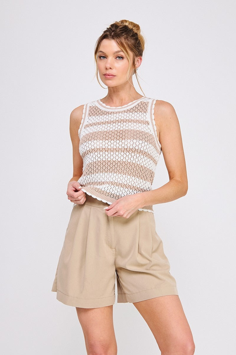 Woman wearing a sheer top and beige shorts on a white background