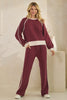 Woman wearing a burgundy tracksuit with white accents against a neutral background