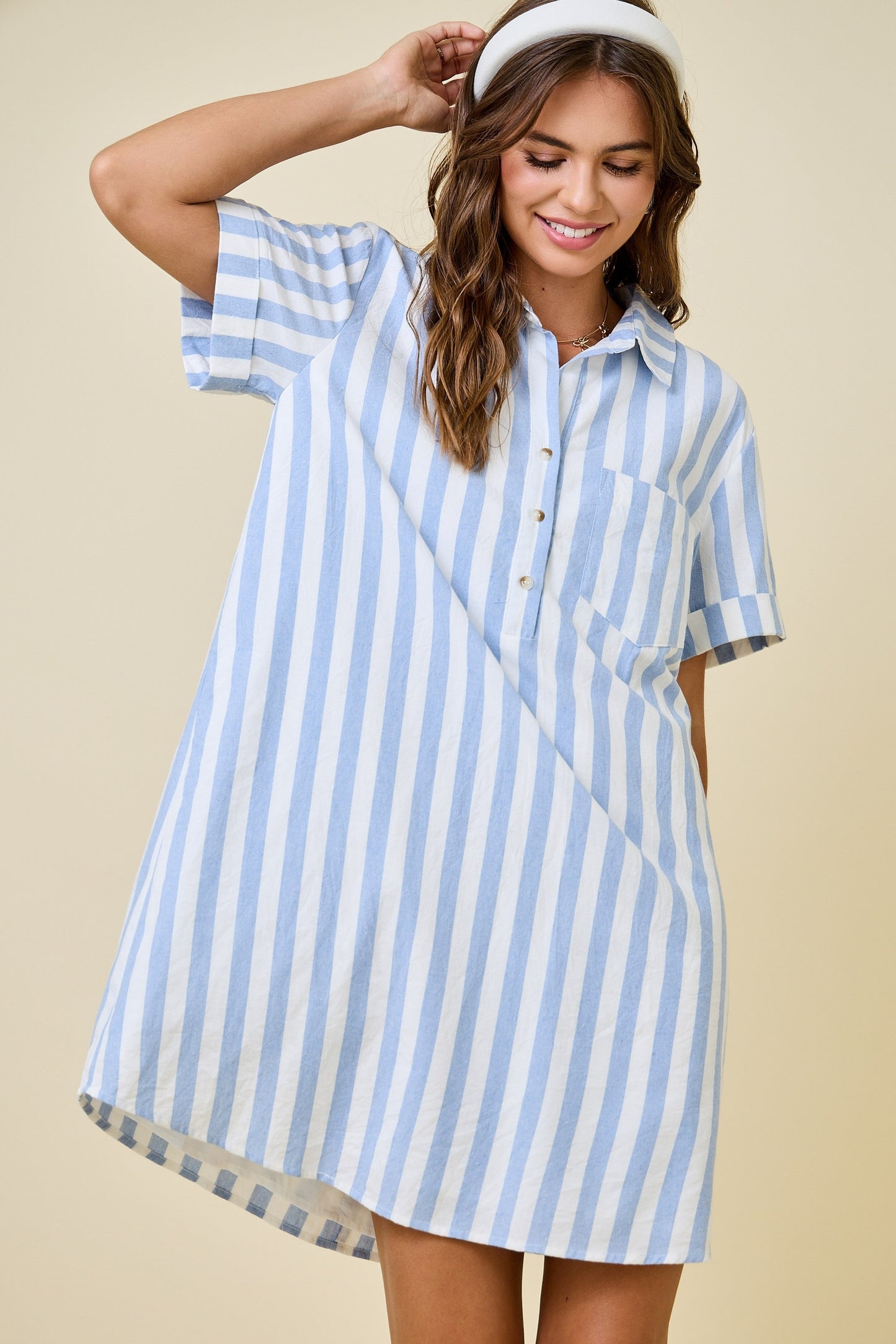 Woman wearing a blue and white striped dress against a beige background