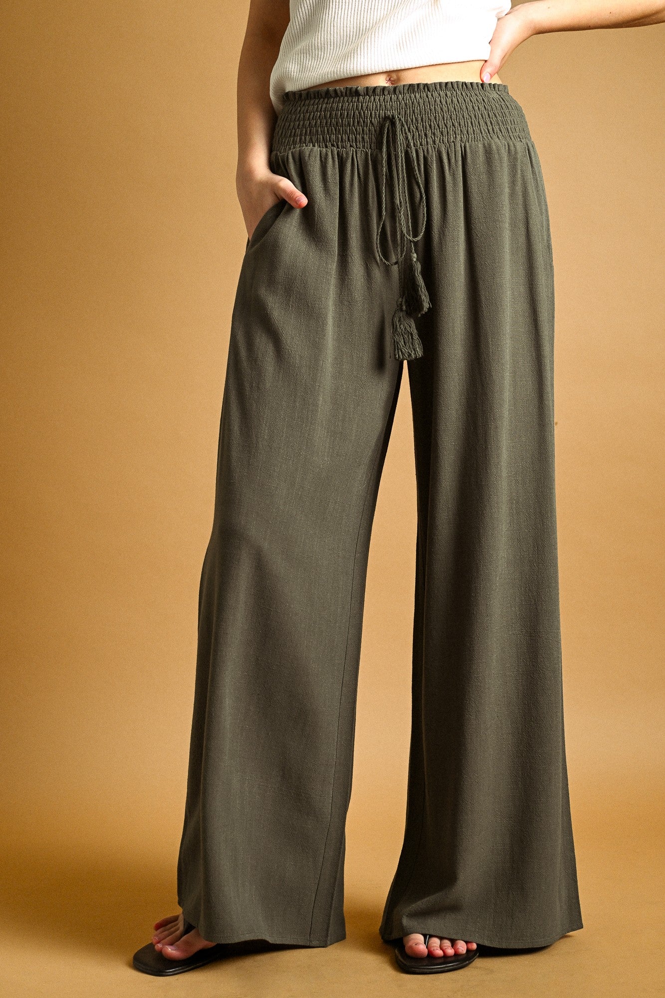 Person wearing olive green wide-leg pants on a beige background