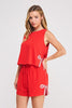 Woman wearing a red romper with bow details on a white background