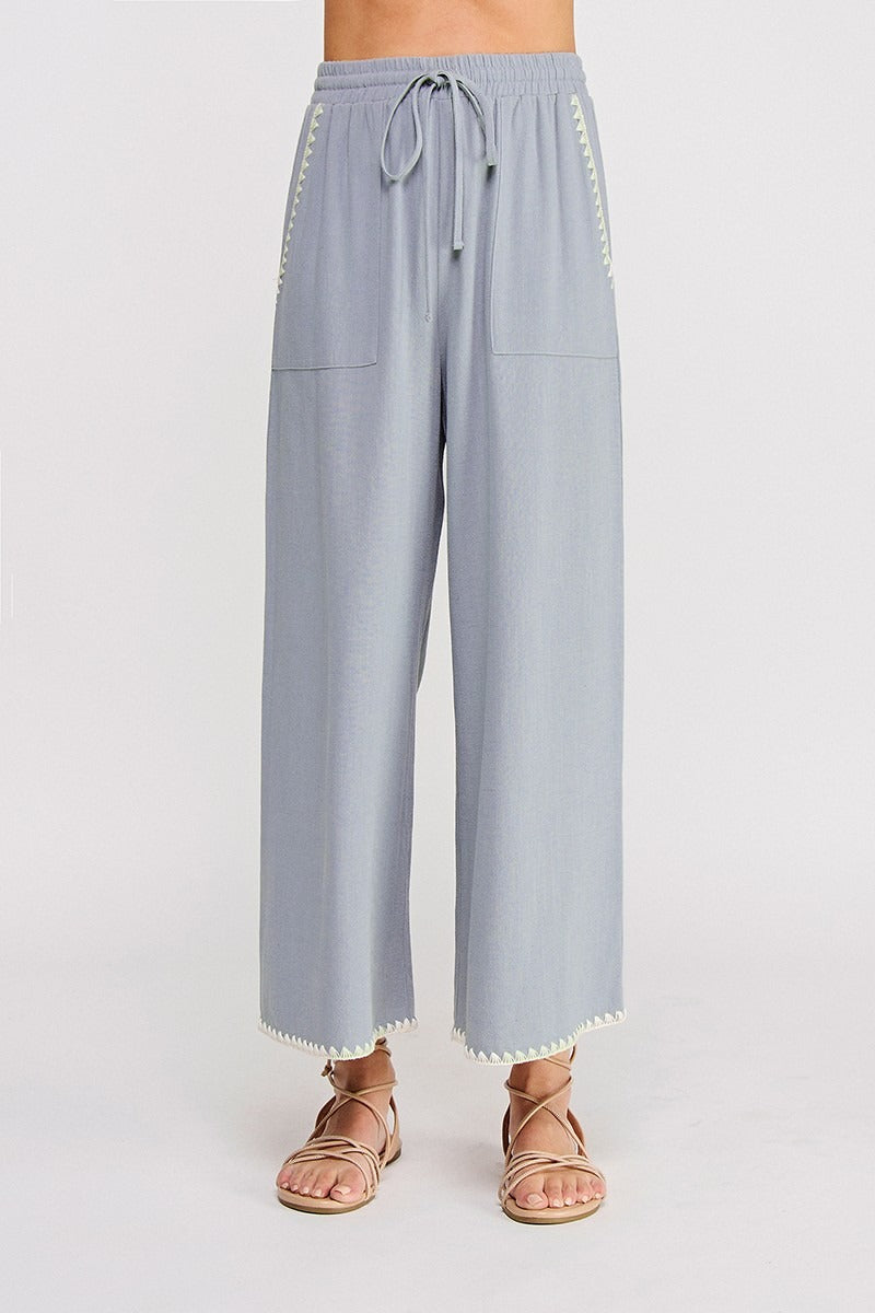 Light blue pants with white trim on a plain background