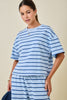 A woman wearing a light blue and navy blue horizontally striped short-sleeve t-shirt, photographed against a solid beige studio background.