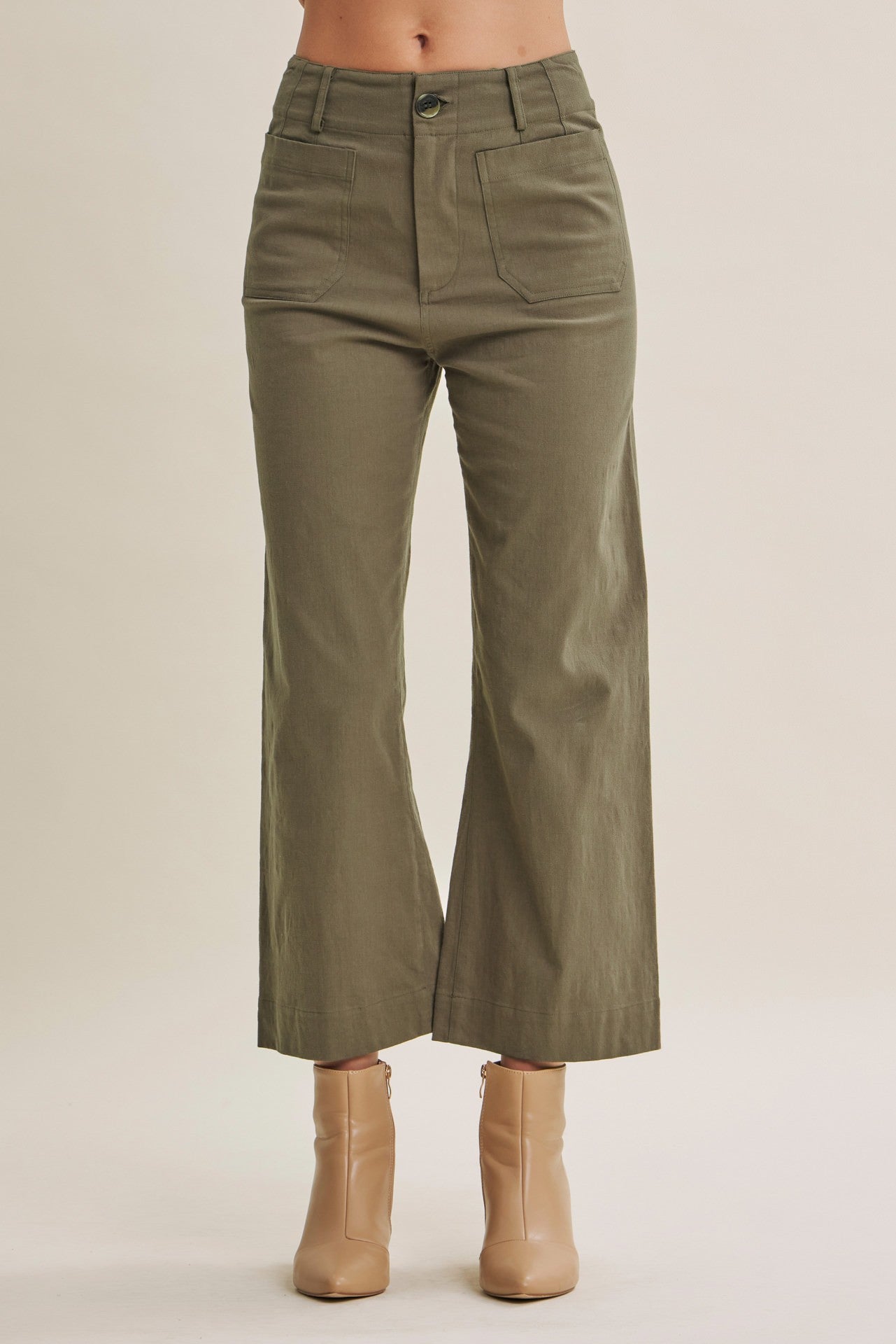 A person wearing olive green wide-leg cropped pants with beige ankle boots, shown from the waist down against a plain light beige studio background.