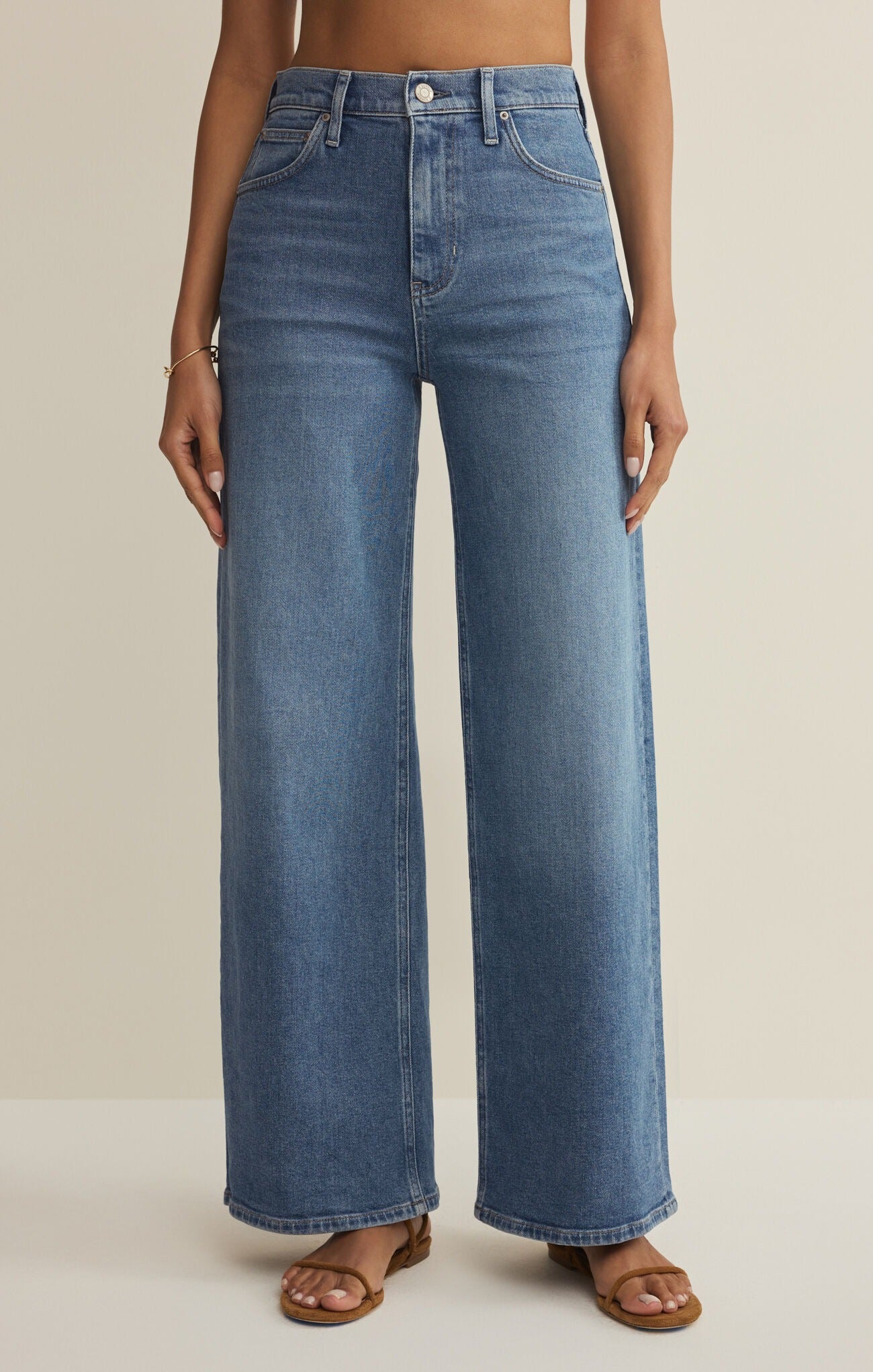 Blue jeans worn by a person on a beige background