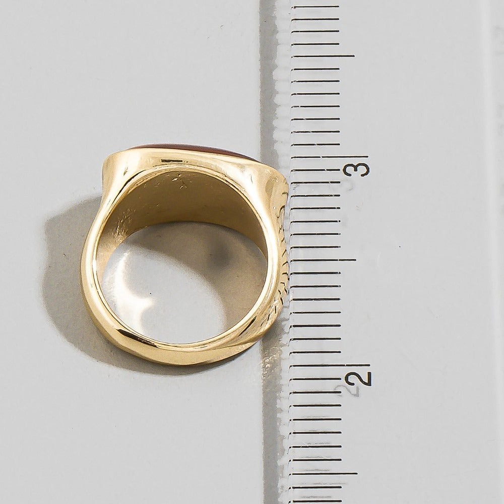 Gold ring next to a ruler on a white background