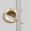 Gold ring next to a ruler on a white background
