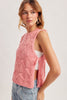 Woman wearing a pink sleeveless knitted top with a white shirt underneath on a light gray background