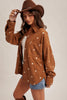 Woman wearing a brown floral-patterned shirt and cowboy hat on a plain background