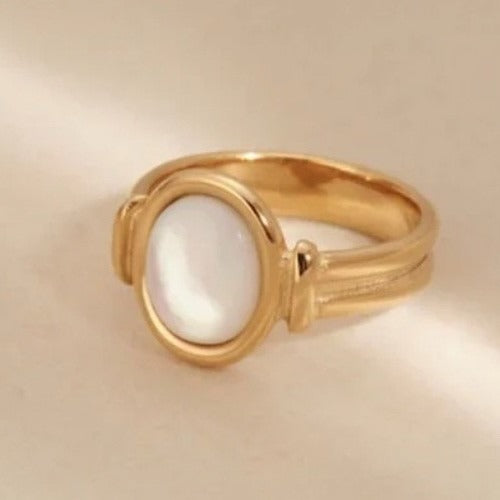 Gold ring with a white stone on a beige background