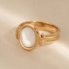 Gold ring with a white stone on a beige background