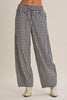 Black and white gingham wide-leg pants with a drawstring waist, modeled with off-white ankle boots against a solid beige background.