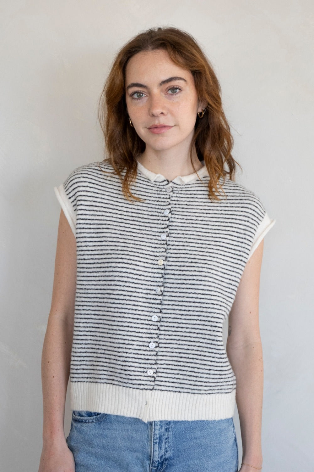 Woman wearing a striped sleeveless top against a plain background