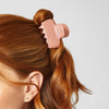Person using a pink hair bun maker on their red hair against a light gray background