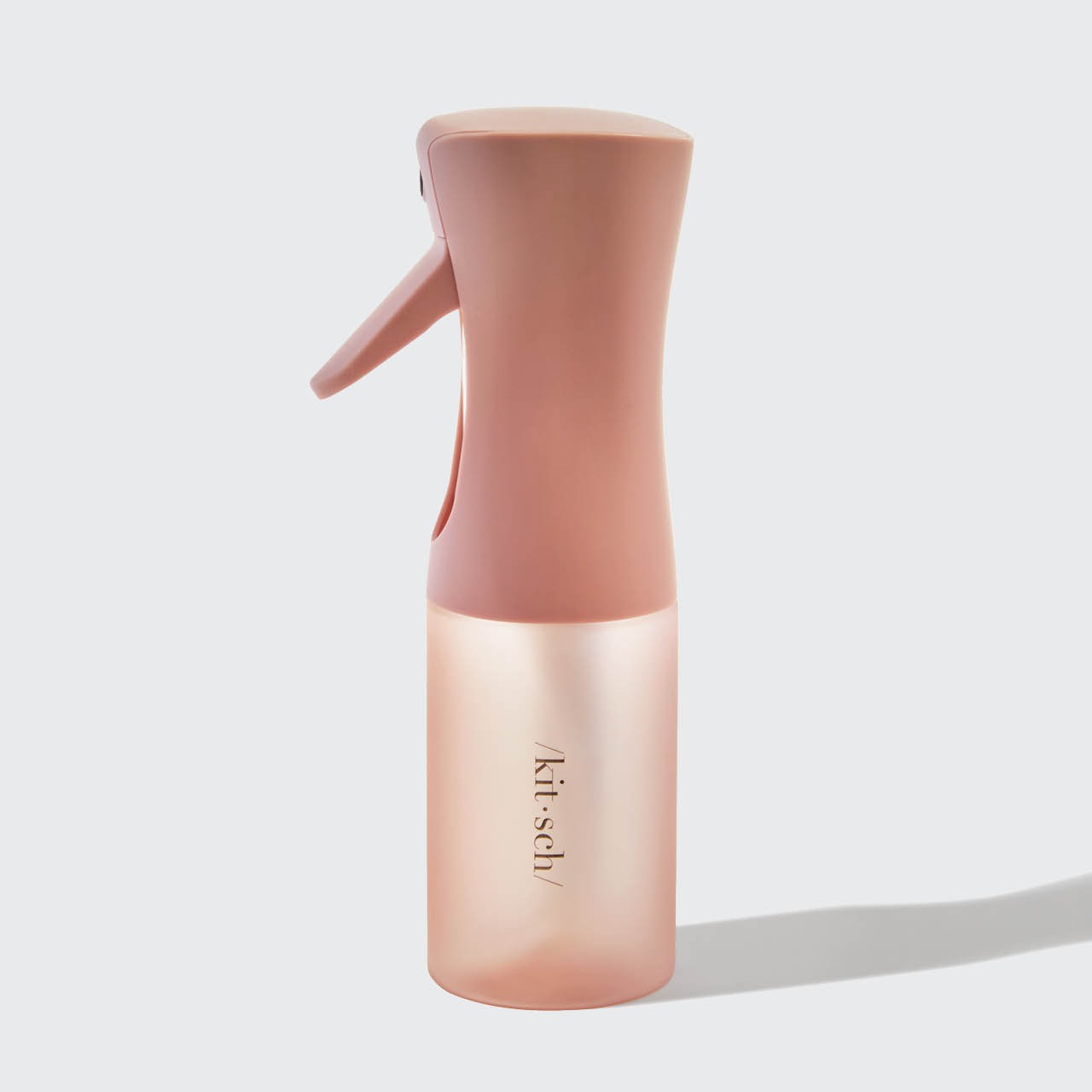 Pink spray bottle with 'kitsch' branding on a light gray background