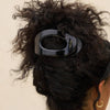 Black hair clip in a person's hair with a neutral background