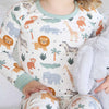 Child wearing pajamas with animal pattern sitting on a white blanket