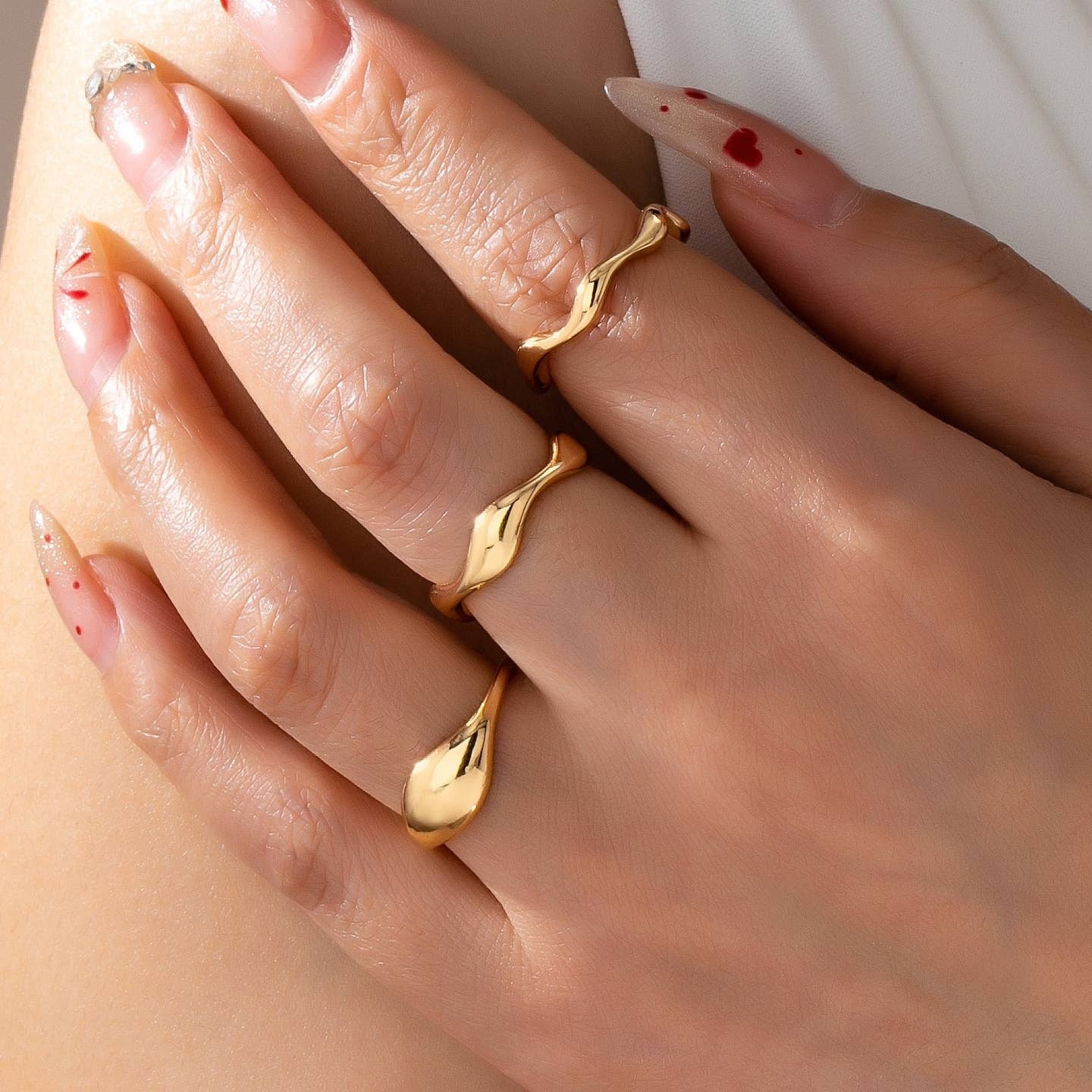 Close-up of a hand wearing gold rings with a soft focus background
