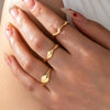 Close-up of a hand wearing gold rings with a soft focus background