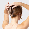 Person using a hair tool to style their hair against a light background