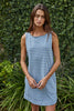 Woman wearing a blue and white striped dress standing in front of green foliage