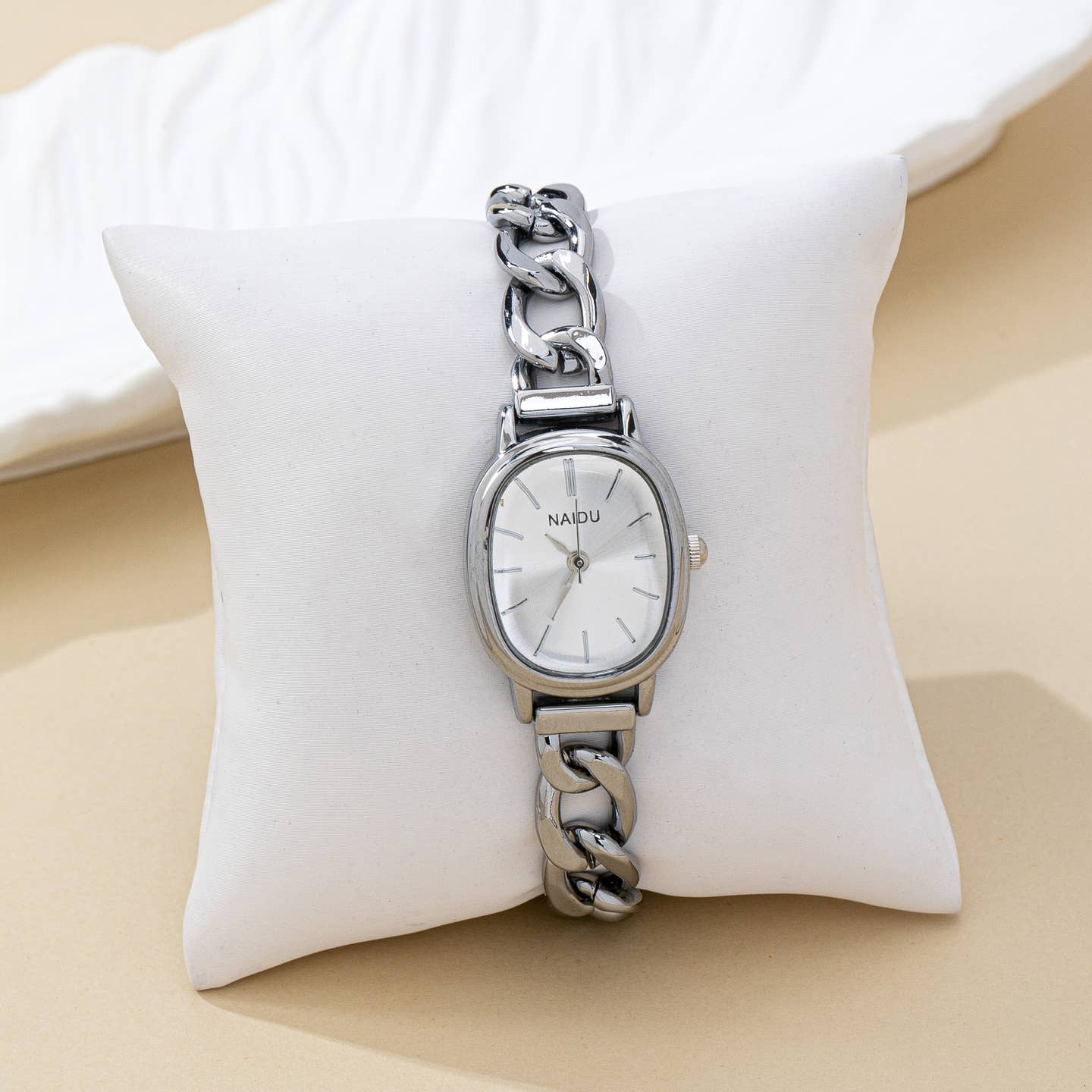 Silver watch with chain strap on a white cushion
