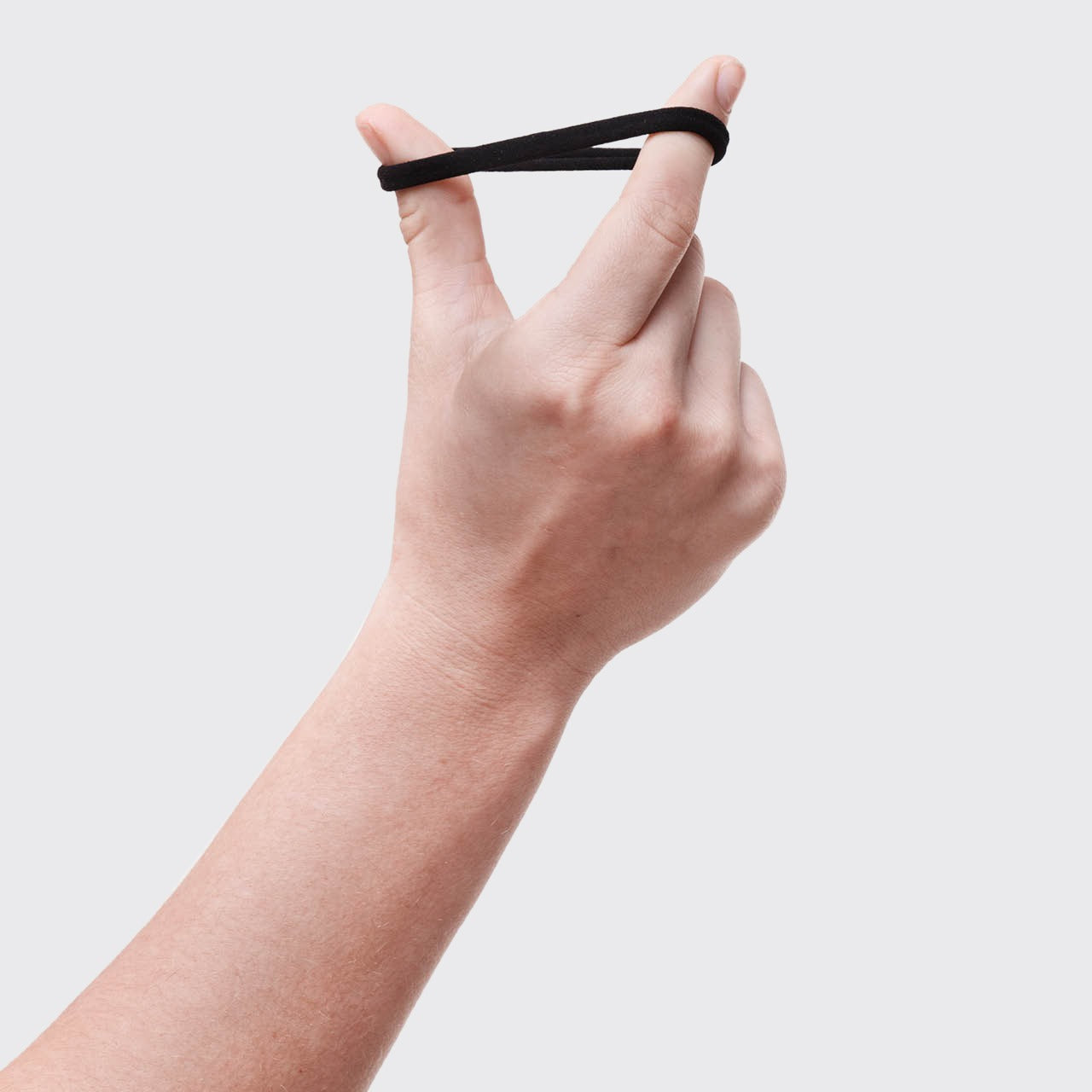 Hand holding a black hair tie against a light gray background