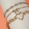 Gold bracelet with heart charm on a white surface