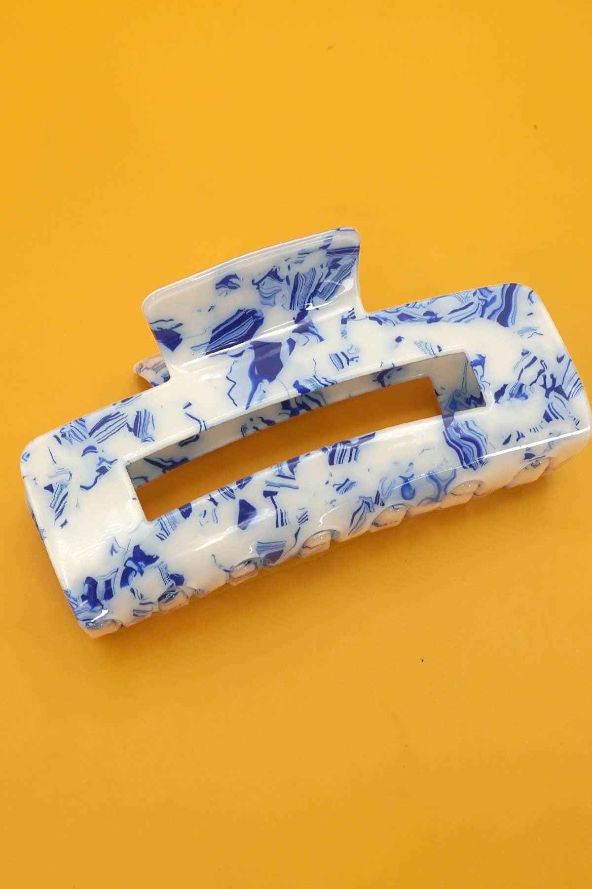 Blue and white patterned hair clip on an orange background