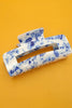 Blue and white patterned hair clip on an orange background
