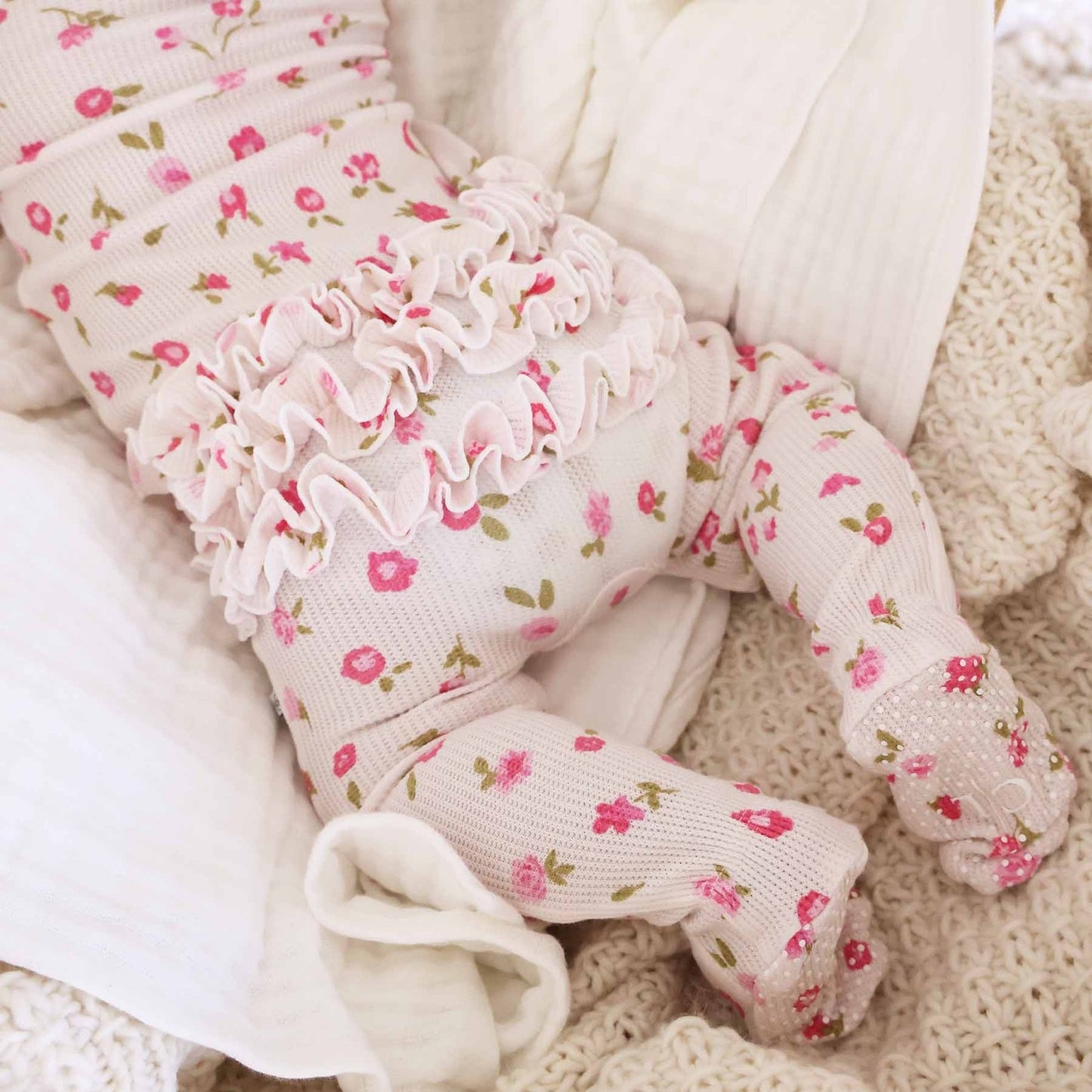 Baby legs wearing floral tights on a soft textured surface