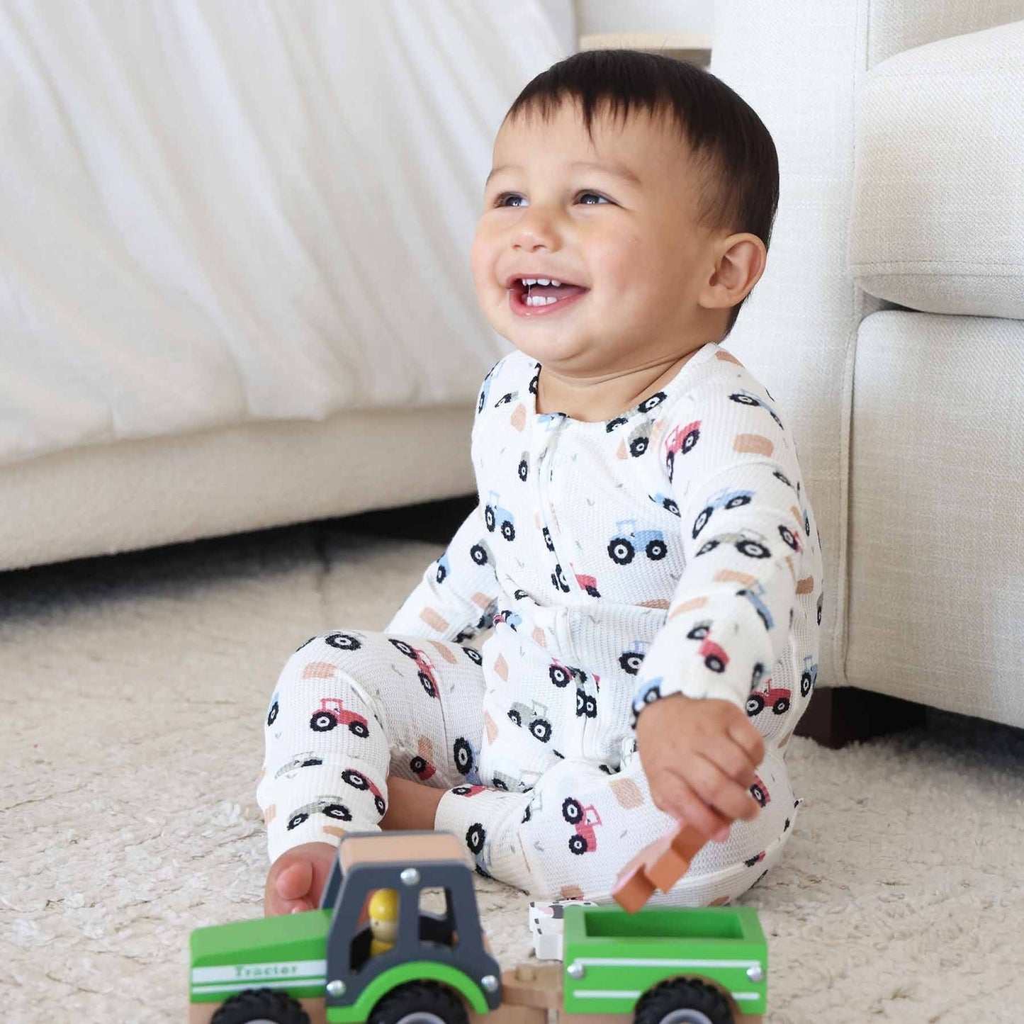 Child playing with a toy truck on a carpeted floor.
