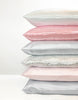 Stack of satin pillowcases in various colors on a white background