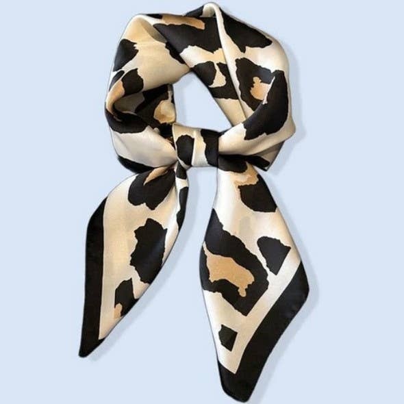 Leopard print scarf tied into a bow on a light blue background