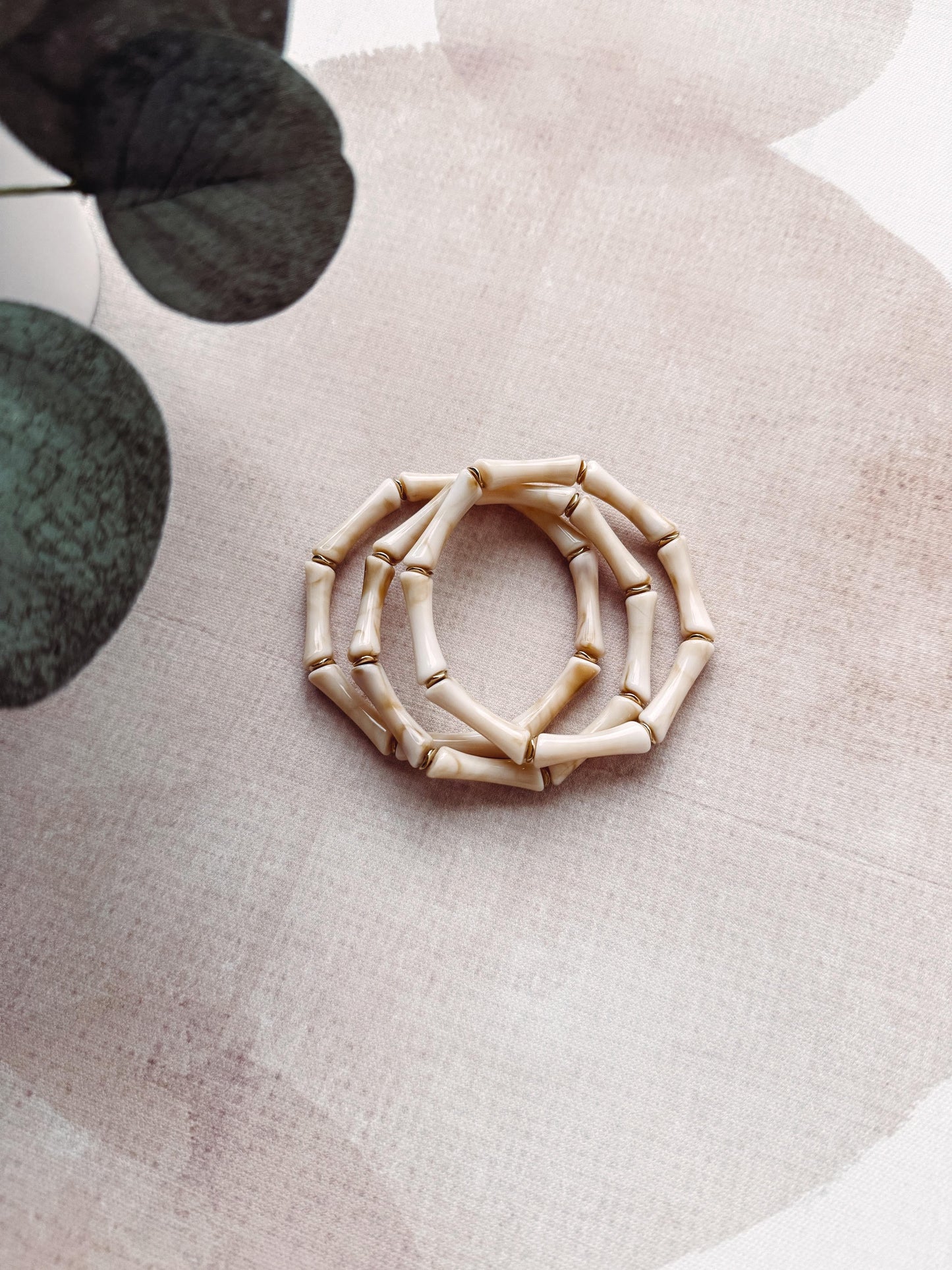 Decorative wreath made of bamboo on a textured surface with green leaves in the background