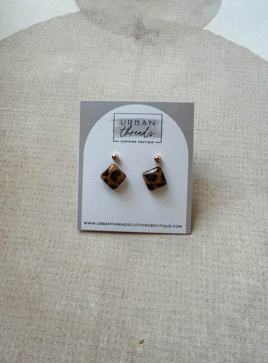 Tortoiseshell stud earrings on a branded card with a beige background